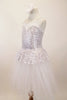 White and silver sequined romantic tutu dress has sweetheart neck-like peplum that sits on top of the long white soft tulle layers. The dress has double straps which cross at back. Comes with hair accessory. Left side
