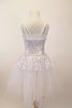 White and silver sequined romantic tutu dress has sweetheart neck-like peplum that sits on top of the long white soft tulle layers. The dress has double straps which cross at back. Comes with hair accessory. Back