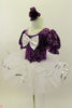 Purple velvet leotard has pouf sleeves & silver pattern. Neck-line is square cut with silver edging & large silver front bow. Comes with white pull-on tutu & floral hair accessory. Left side
