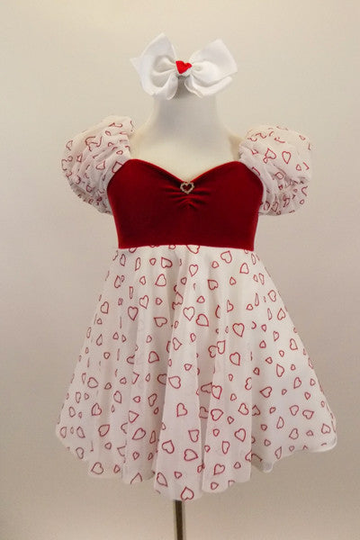 Dress has red velvet sweetheart bodice with open back and small crystal heart accent. The pouf sleeves and skirt are flowy white mesh with small red hearts. Comes with bow hair accessory. Front
