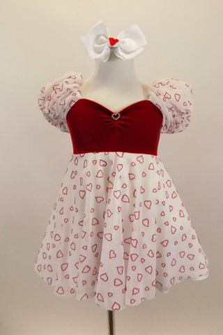 Dress has red velvet sweetheart bodice with open back and small crystal heart accent. The pouf sleeves and skirt are flowy white mesh with small red hearts. Comes with bow hair accessory. Front
