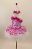 White satin leotard has fuchsia polk-a-dot overlay with bodice ruffle and attached skirt which sits on top of white tutu. Has matching satin ruffled clown hat. Left side
