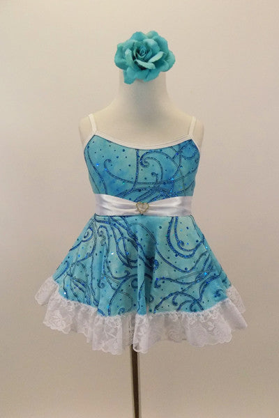 Camisole leotard dress has swirls of blues on aqua base. Has a white petticoat and wide lace trim. White satin waist sash had a crystal heart. Has floral hair accessory. Front
