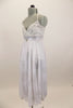 White leotard dress has long skirt with silver floral pattern. Empire waist has silver sequined waistband with crystal brooch. Has matching  hair accessory. Left Side