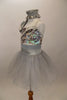 Silver two piece costume has camisole biketard with silver sequined bust Has an attached asymmetrical stretch-satin shrug & separate silver crystal tulle skirt. Comes with hair accessory and white gloves. Left side