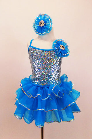 Hologram sequins cover stretch satin bodice of turquoise ruffled camisole dress. Jeweled rosettes accents the left shoulder and hair matching hair accessory. Front