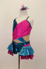 Nude mesh base leotard has metallic fuchsia-turquoise cross over front with crystals.  Shorts have layers of pleated ruffles. Comes with matching hair accessory. Left side