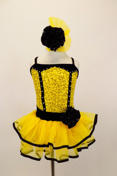 Yellow sequin leotard has black velvet accents with crystals. Black satin rosettes accent the waist & hair accessory. Has ruffle layer skirt with black trim. Front
