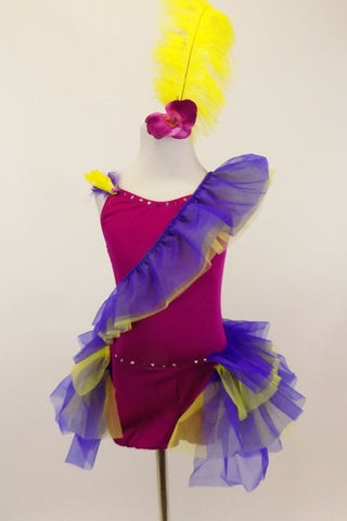 Magenta camisole biketard has crystals & feather accents. Asymmetrical  purple & yellow ruffle crosses the bodice & open front bustle. Has yellow hair feather. Front