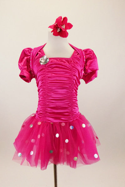 Hot pink stretch satin ruched dress has attached bolero with crystal accents,a  tulle skirt with silver polka dots & pouf sleeves. Comes with hair accessory. Front