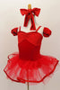 Red princess-cut camisole leotard has floral pattern bust area and matching arm poufs. There is a red pull-on tutu skirt with ribbon edging & matching hair bow. Side