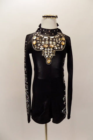 Long sleeved black biketard has high collar, low open back with 3 straps& crystals. Sleeves have silver zig-zag pattern and large jeweled bib. Has hair clip. Front