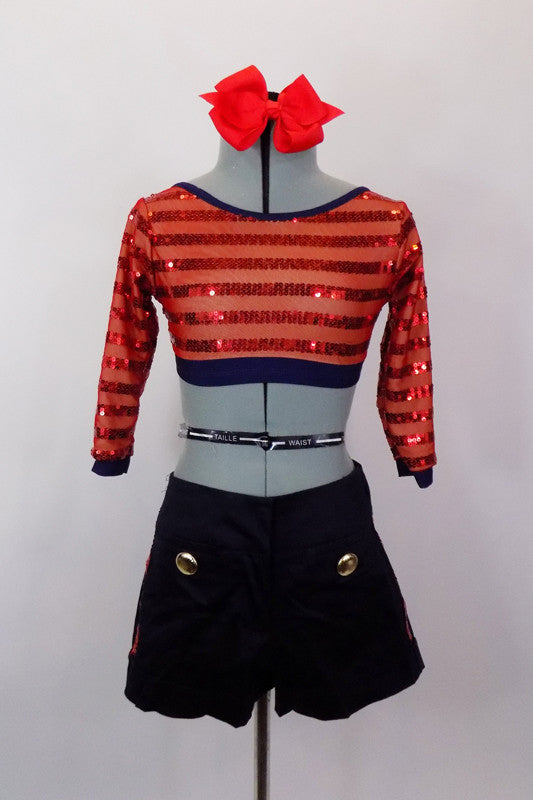 Two piece costume has navy high-waisted shorts with gold buttons. The red open back, long sleeved crop-top has sequined stripes. Comes with bow hair accessory. Front