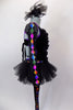 Black velvet unitard has black tutu skirt. Legs and sheer arms have colorful design lined with crystals. Bodice had low V-front held by straps & ruffled collar. Comes with hair accessory. Side