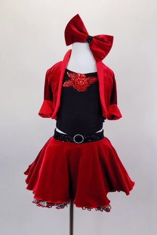 Red velvet skirt has ruffled black petticoat & crystaled waistband. Has red velvet short jacket over black crop-top with sequin accent. Has red velvet hair bow. Front