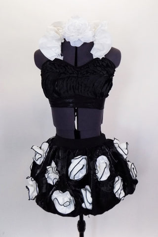 Black pleated, satin bra top has lace-up back & large white ruffle halter collar. Matching bubble skirt is adorned with oversized rosettes. Comes with hair accessory. Front