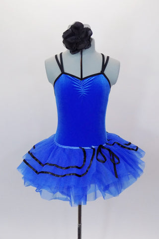 Royal blue ballet tutu has layers of blue ruffled tricot with black ribbon accented. The attached blue velvet bodice has black cross straps. Comes with floral hair accessory. Front