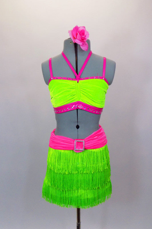 Neon green fringe skirt has pink gathered waistband with crystal buckle. Matching half-top has  pink leatherette banding and straps. Comes with hair accessory. Front
