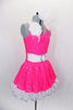 Neon pink dress has white spandex belt with crystal buckle. Has white ruffled underskirt for volume. Keyhole back attaches by a ring. Comes with hair accessory. Right side