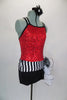 Biketard has red sequin bodice with black double cross straps,. Accented with black & white stripe waistband, large white curly side bustle, attached black shorts & hair accessory. Right ide