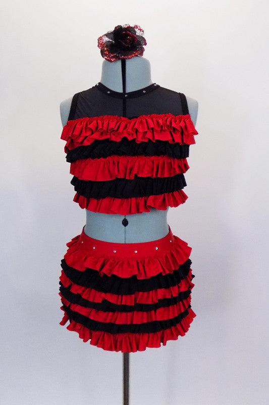 Two-piece costume has layers of red and black ruffles. The half top has three back straps for closure & black mesh upper with crystals to match ruffles bottom. Comes with floral hair accessory. Front