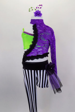 Black & white striped unitard has one long & one short leg with purple & black hip bustle. It's attached to purple lace asymmetrical shrug with green bra below. Comes with hair accessory. Front