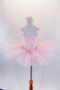 Pale pink satin leotard has wide adjustable straps and cameo  brooch. Comes with a pull-on 7-layer pale pink tutu skirt and floral hair accessory. Back