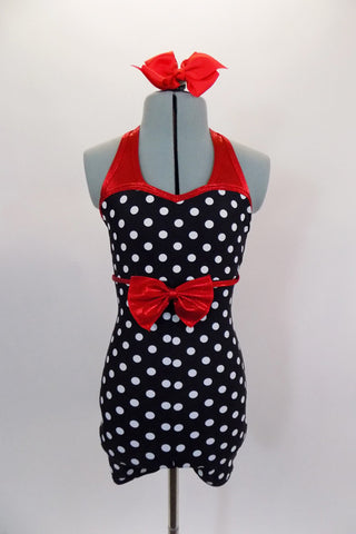 Black and white polka dot short unitard has red metallic banding and halter neck. The waist has a large red metallic bow. Comes with red bow hair accessory. Front