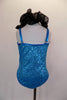 Turquoise sequin leotard has pinch front & halter neck with an attached wide, black curly organza ruffle & adjustable straps. Comes with hair accessory. Back