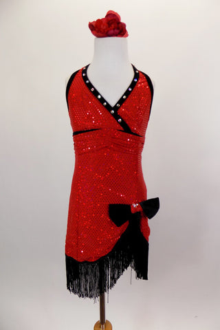 Flapper themed red sequined cross front halter dress has black crystaled piping. Skirt cuts up at left leg with black velvet bow. Edged with black fringe. Front