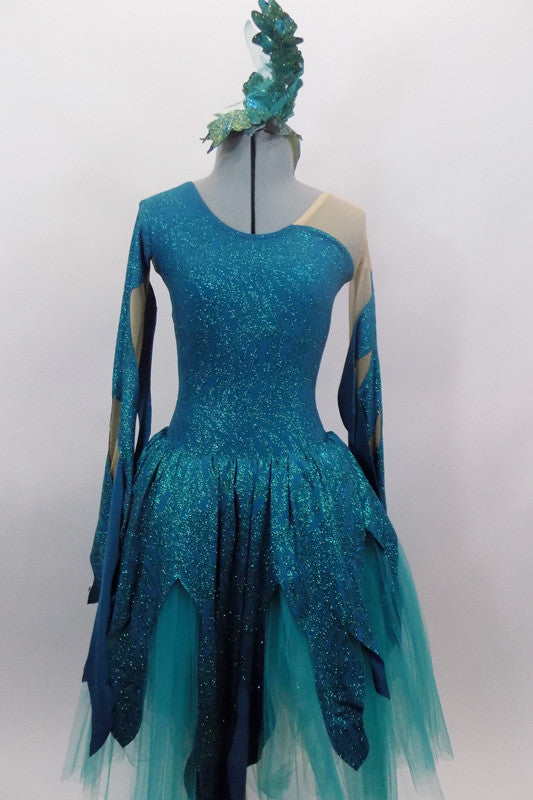 Glitter teal & nude mesh asymmetrical dress has long flowy sleeves that mimic the waves of the ocean. The skirt overlay peaks & rest on layers of aqua tulle. Comes with matching hair accessory. Front