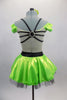 Lime green dress has nude torso with attached green bra top that has cap sleeves. Back has triple black straps joined by crystal ring. Skirt had black petticoat & crystal accents. Comes with hair accessory. Back