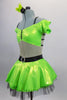 Lime green dress has nude torso with attached green bra top that has cap sleeves. Back has triple black straps joined by crystal ring. Skirt had black petticoat & crystal accents. Comes with hair accessory. Left side