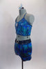 Turquoise iridescent, silver swirl two -piece costume has half top with cross back straps and crystal brooch accent. The matching shorts have a teal glittery waistband with crystal ring buckle accent. Comes with matching hair accessory. Side