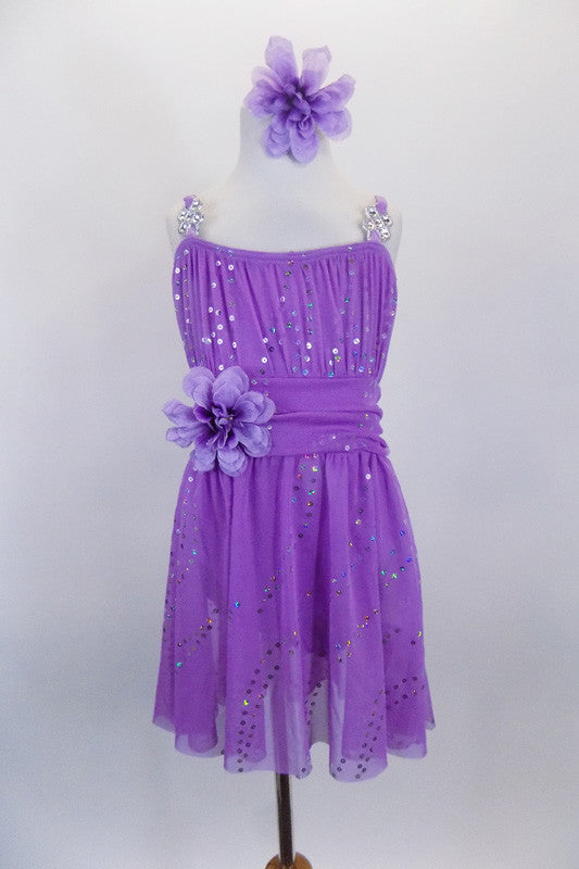 Lavender sequined sheer leotard dress has gathered front bodice with crystal accents Low open back has cross straps. Wide waistband gathers in bow knot at back. Has large flower at waist and matching hair accessory. Front