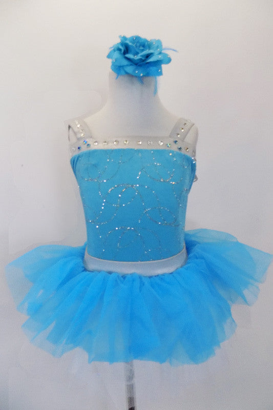 Turquoise velvet leotard has silver swirls with crystal covered silver banding & deep open back. The pull-on tutu has silver waistband & turquoise tulle.  Comes with floral hair accessory. Front