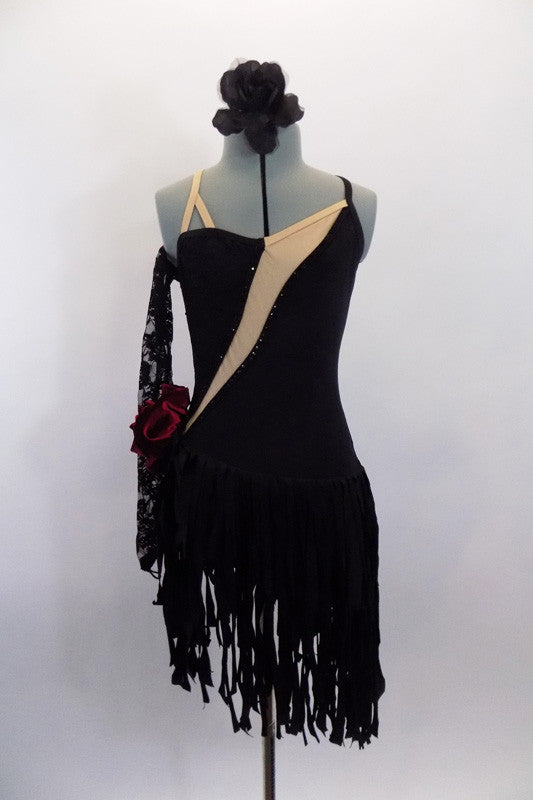 Black dress has wide fringy skirt bottom & angled, nude mesh insert. The dress has a low open back with cross straps, lace gauntlet & velvet rose at left hip. Front