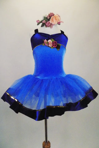 Blue tutu has deep blue velvet bodice with gold trim & cross straps. The tulle skirt has blue velvet trim accent. Front has rose detail & matching hair piece. Front