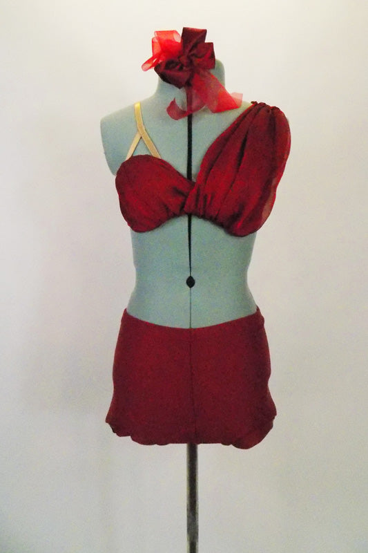 Deep red two- piece costume has bra covered with softly pleated chiffon that cascades over the left shoulder. Has matching deep red shorts and hair accessory. Front