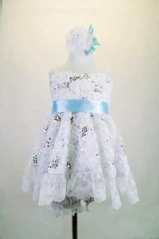 White sequined rose lace baby-doll dress has wide lace ruffle edge & wide satin baby blue sash. The back has lace-up closure. Comes with lace edged bloomers. Front
