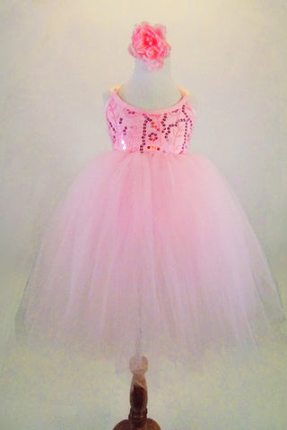 Romantic tutu dress in pale pink lace has layers of soft tulle attached to sequined bodice. Wide pink satin ribbon from shoulders cross & lace up at back.  Comes with hair flower. Front