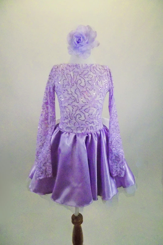 Pale lilac long sleeved dress has sequined bodice with boat neck & low open back. Attached satin skirt has a separate crinoline & large white bow at low back . Comes with lilac floral hair accessory. Front