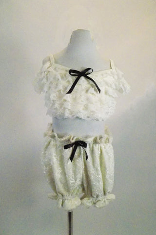 2-piece ivory lace costume resembles vintage undergarments. Bottom is pouffy bloomers & bra top has lace ruffled, front, corset  lace-up back & drop shoulders. Comes with large hair accessory. Front