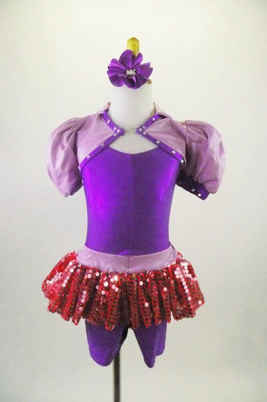 Purple short leotard has attached pink sequined short skirt with lavender waistband. The accompanying lavender shrug has pouf sleeves & crystaled purple piping. Comes with purple hair accessory. Front