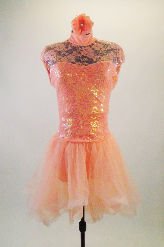 Peach sweetheart bodice dress has boat-neck sequined lace overlay with keyhole back. Attached high-low skirt is layers of tricot with stiff looping edge. Comes with matching floral hair accessory. Front