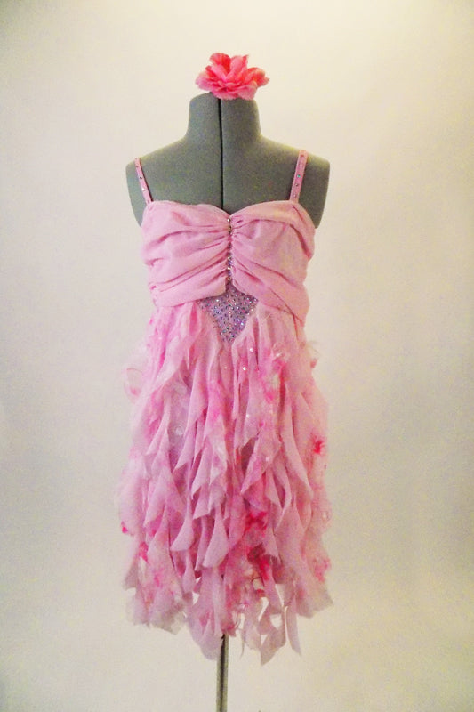 Delicate pink chiffon A-line dress has a bottom of soft cascading ruffles. The front centre torso and straps are covered in straps. Comes with matching floral hair accessory. Front