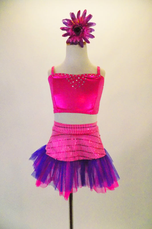 This sweet two-piece costume has pink half a top with crystal accents at front and back. The accompanying skirt has tone on tone pink striped patterns with a wide pink and purple tulle ruffle edge. Comes with pink/purple daisy hair accessory. Front