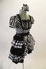 Black and white striped saloon girl themed dress has a laced bib bust area and short pouffe sleeves. The right hip is gathered with pick-ups in layers of black and black/white checkers. The back of the dress has lace-up detail. Comes with matching hair accessory. Right side