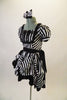 Black and white striped saloon girl themed dress has a laced bib bust area and short pouffe sleeves. The right hip is gathered with pick-ups in layers of black and black/white checkers. The back of the dress has lace-up detail. Comes with matching hair accessory. Left Side