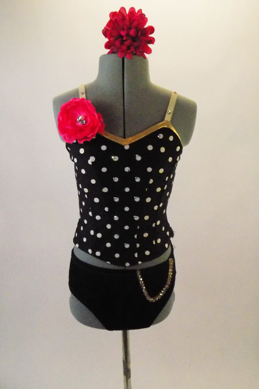 Two-costume has black and white polka dot camisole top with gold piping and jewelled flower accent at right shoulder. The matching black briefs have a chain accent at the left hip. Comes with matching hair accessory. Front